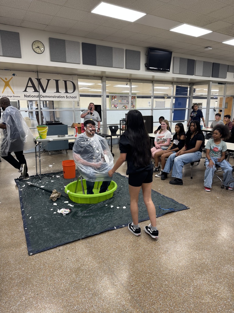 Students throwing a pie at a staff member  during a field Day activity.