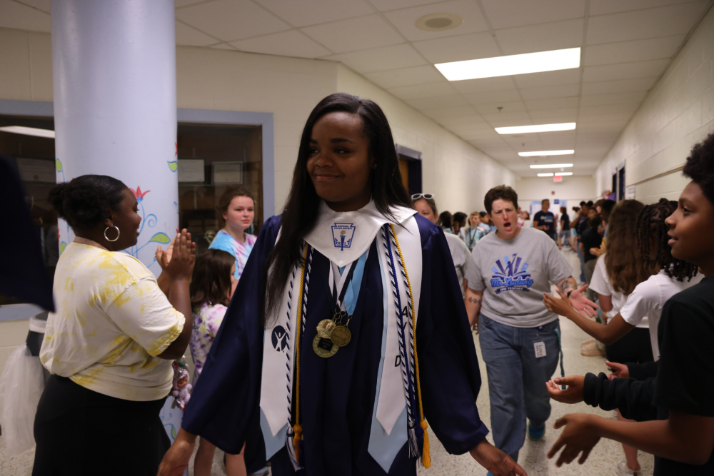 Close up of IRH student walking down the hall with SRI students lining the halls.