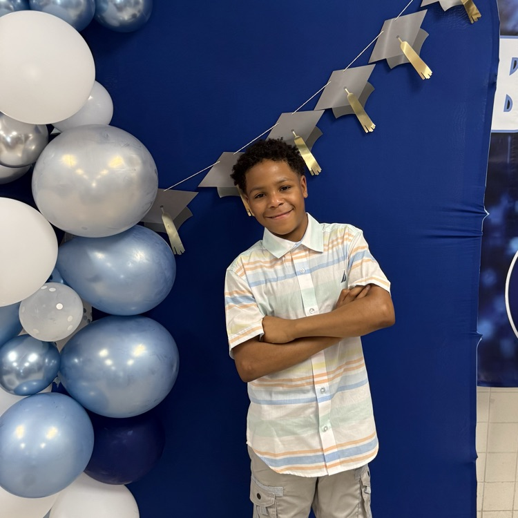 Student at the photo opt balloon backdrop smiling. 