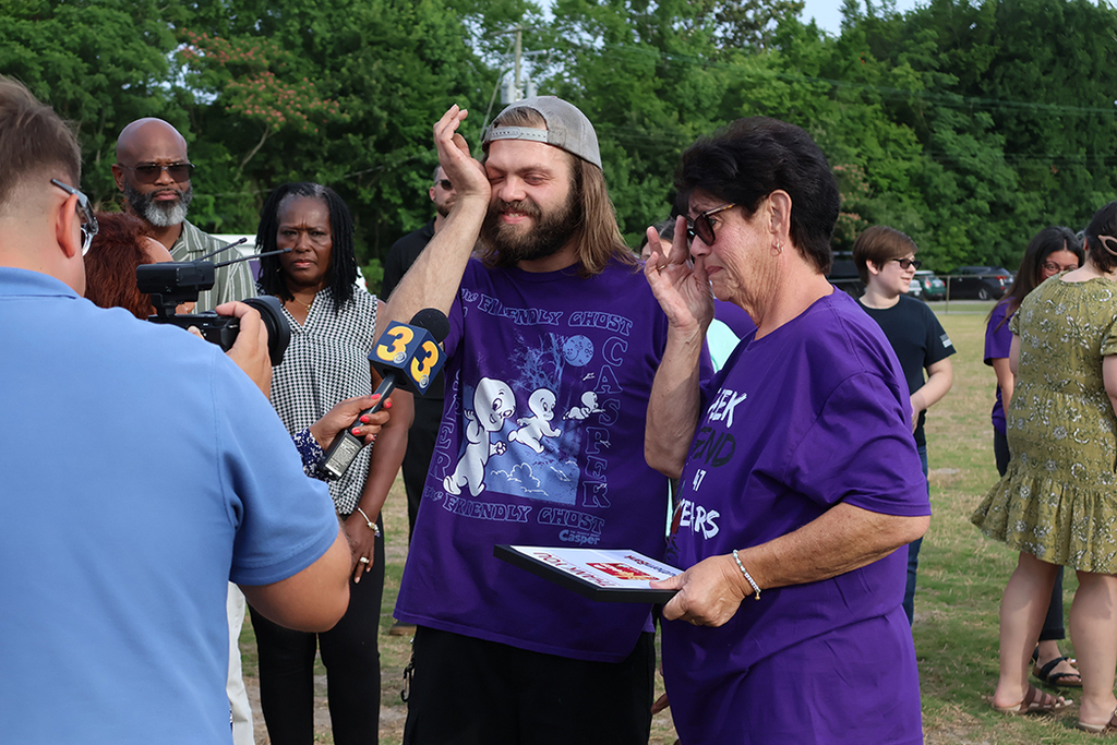 Teacher with former student being interviewed by report. Both with tears in their eyes.