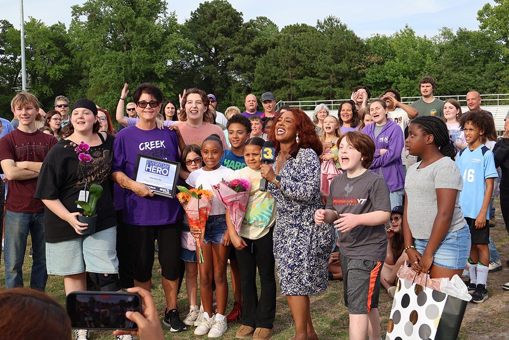 Group of students gathered around teacher to celebrate her retirement.