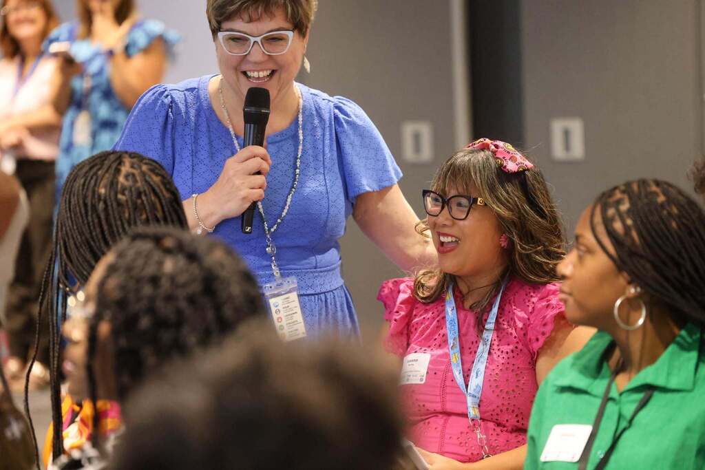 An educator leading a discussion smiling with other educators at the conference.
