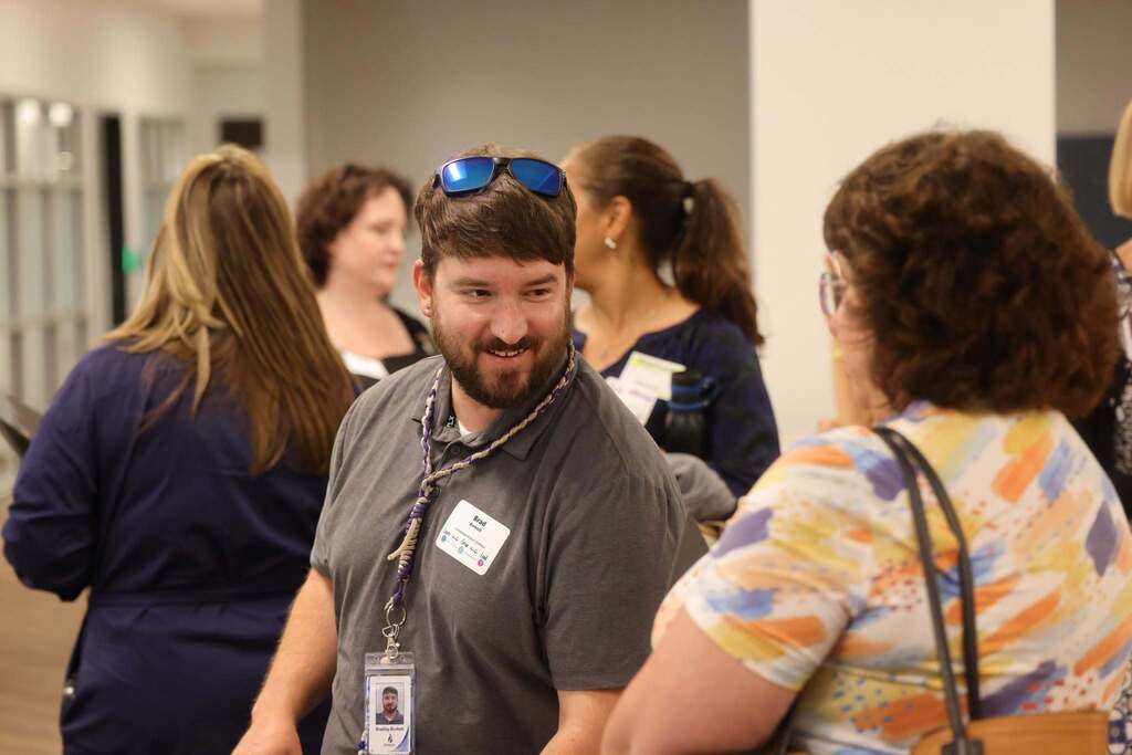 A male educator talking with another coworker at the conference.