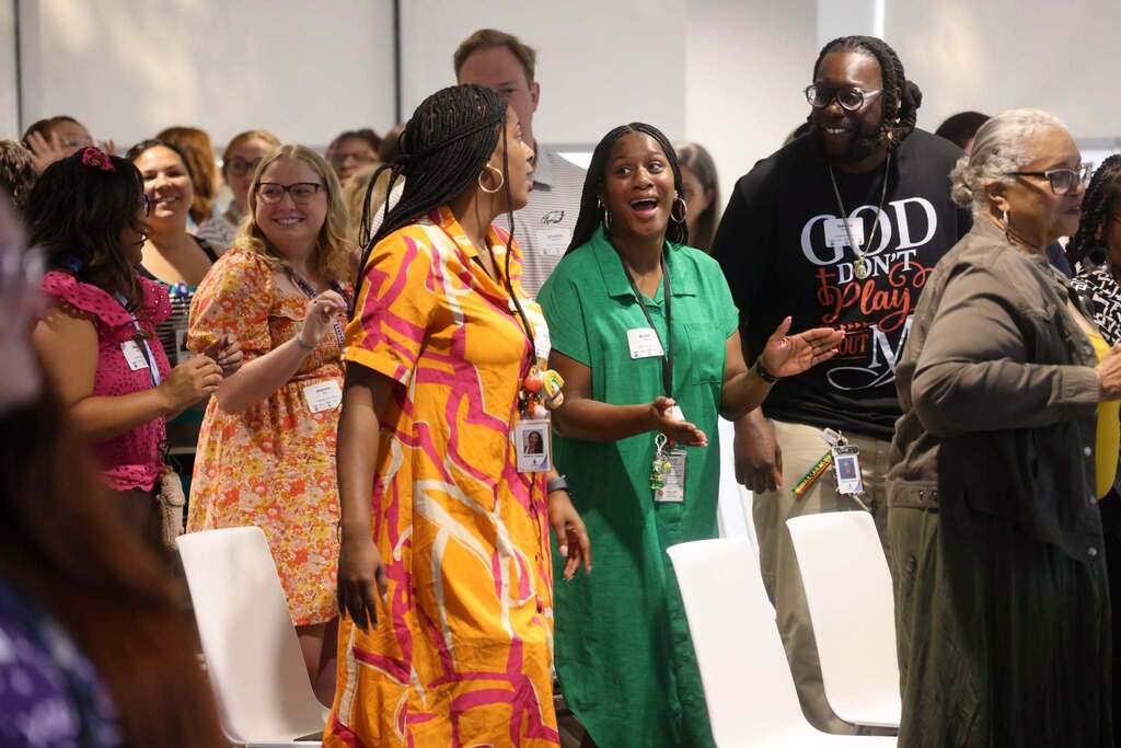 Educators standing and clapping at a conference.