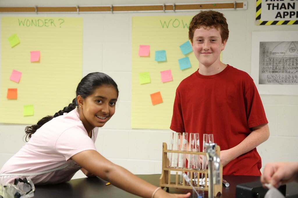 2 students smile while cleaning up lab space