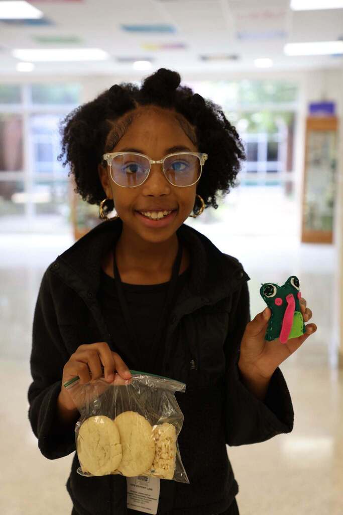 student proudly shows off her sewing creation