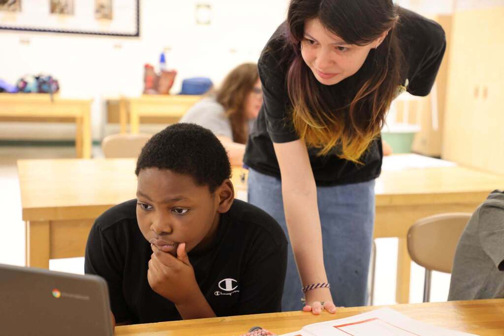student teacher observes student as he works on chromebook