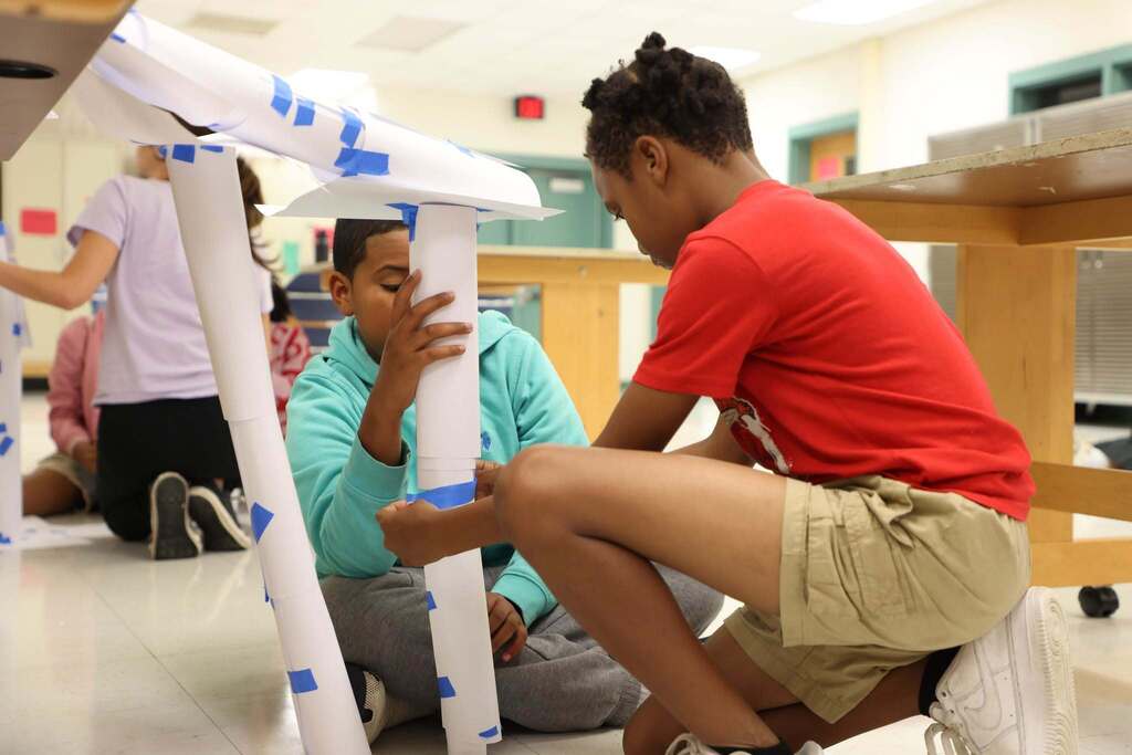 students focus on building a paper bridge