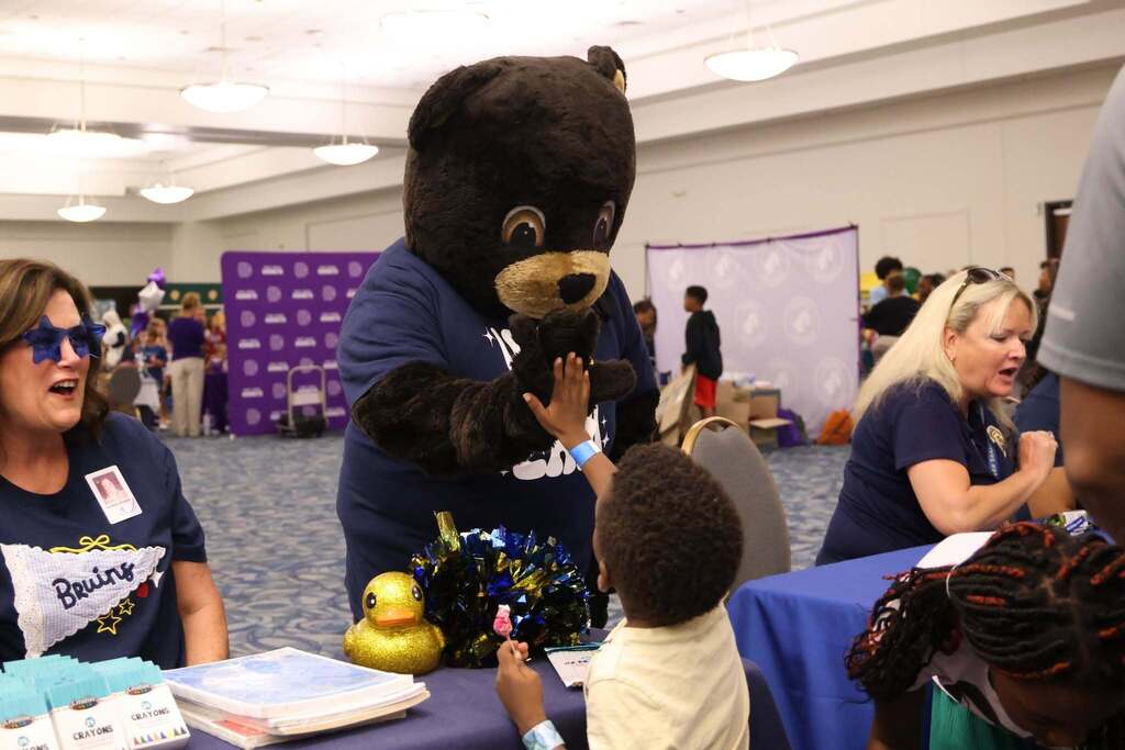 happy student receives high fives from bruin mascot