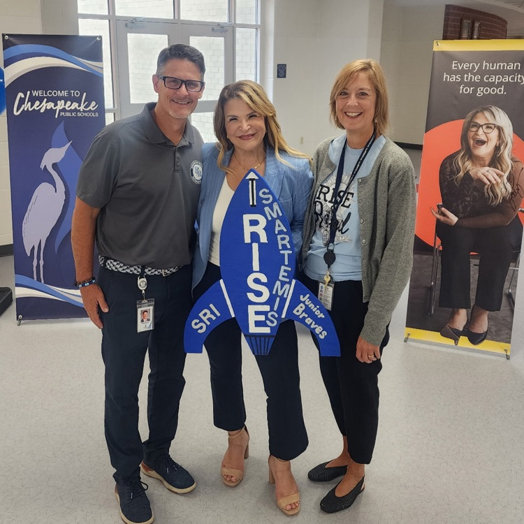 Wooden rocket cutout Smartemis posing with Mr. Triolet, Mrs. Boerboom, and School Board Chair Kim Scott at the Empowerment Conference