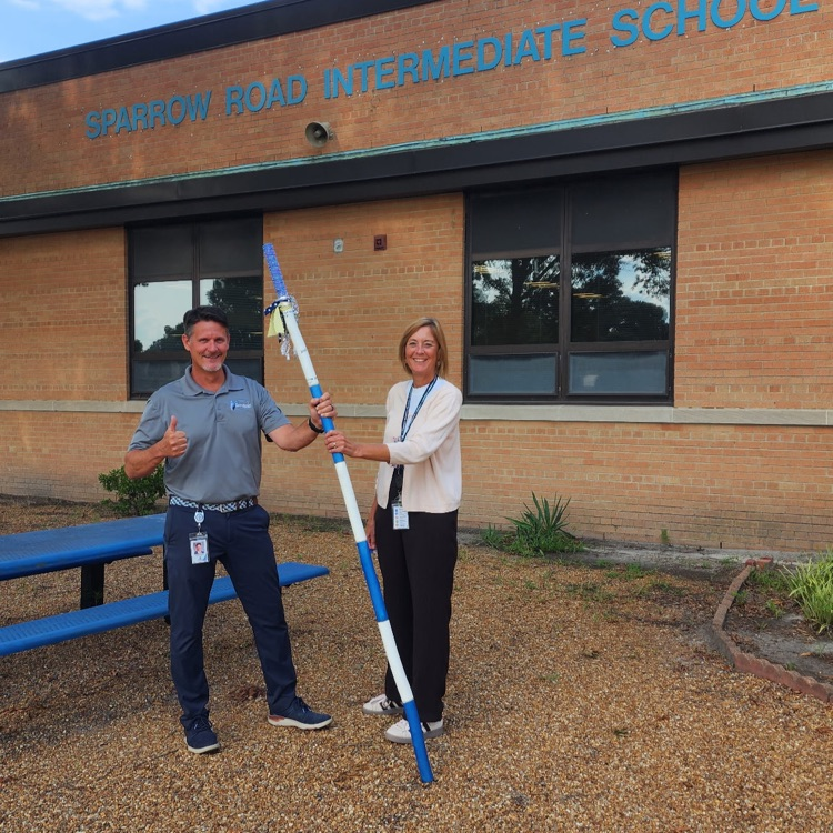 Mr. Triolet and Ms. Boerboom with the spirit stick in front of SRI.