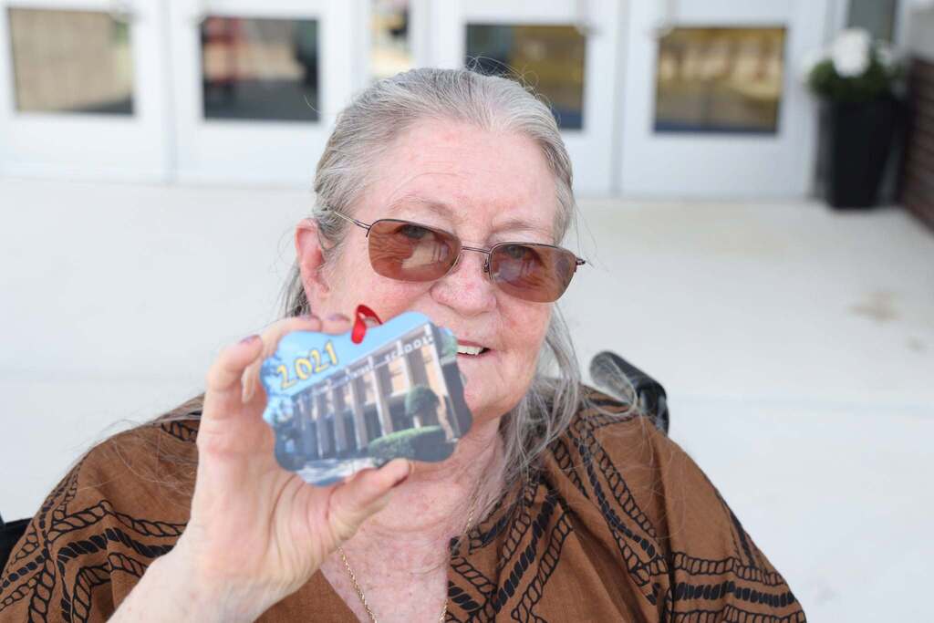 Ms. Chittum proudly holds ornament with image of orginal Chittum