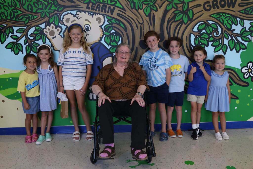 Ms. Chittum smiles in front of mural with current students