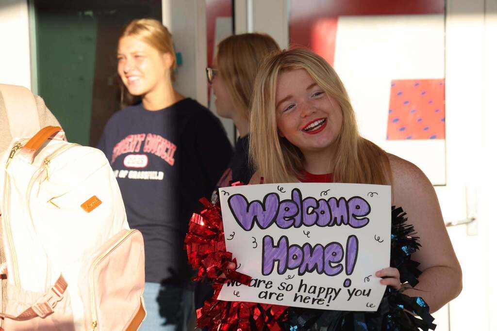 student waits and greets new teachers