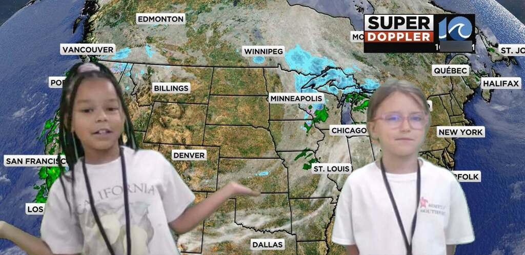 students smile in front of weather board