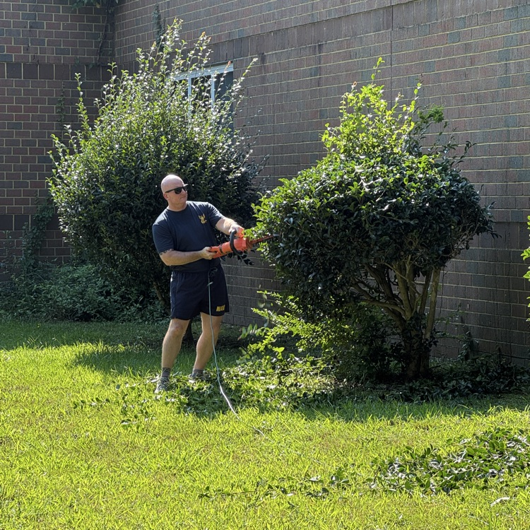 military volunteer trimming a hedge