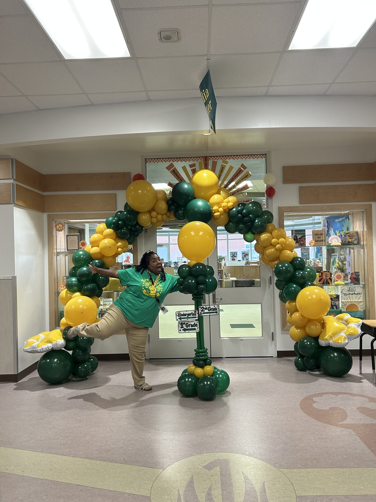 Mrs. Harris excitedly posing in front of her balloon arch masterpiece that she put together for Meet and Greet