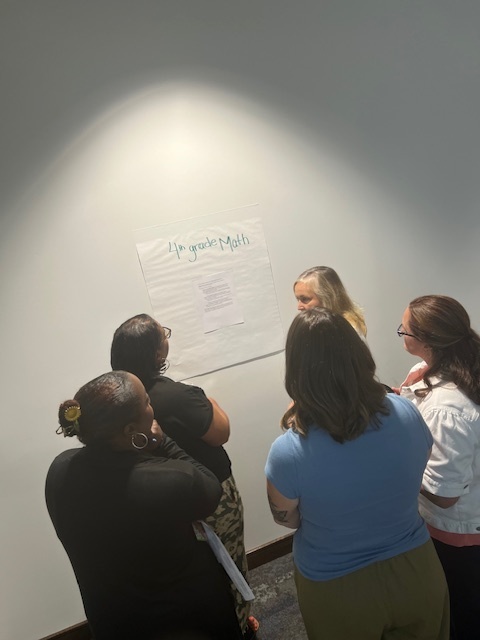 group of teachers writing on a poster board with post-its
