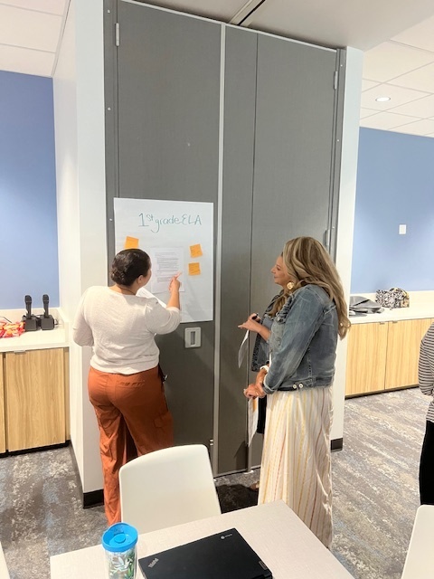 group of teachers writing on a poster board with post-its