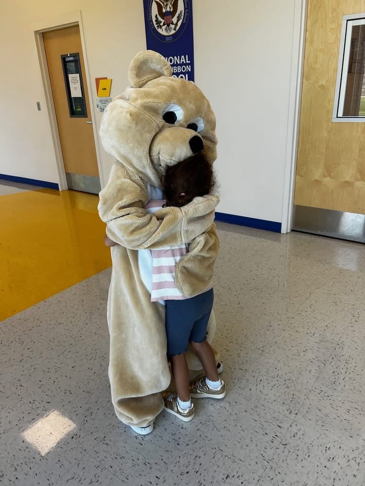 Chester, the bear hugging a student