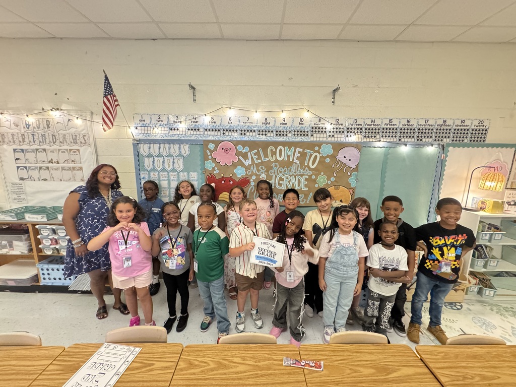 Ms. Roselle and her second grade students posing with first day of school sign