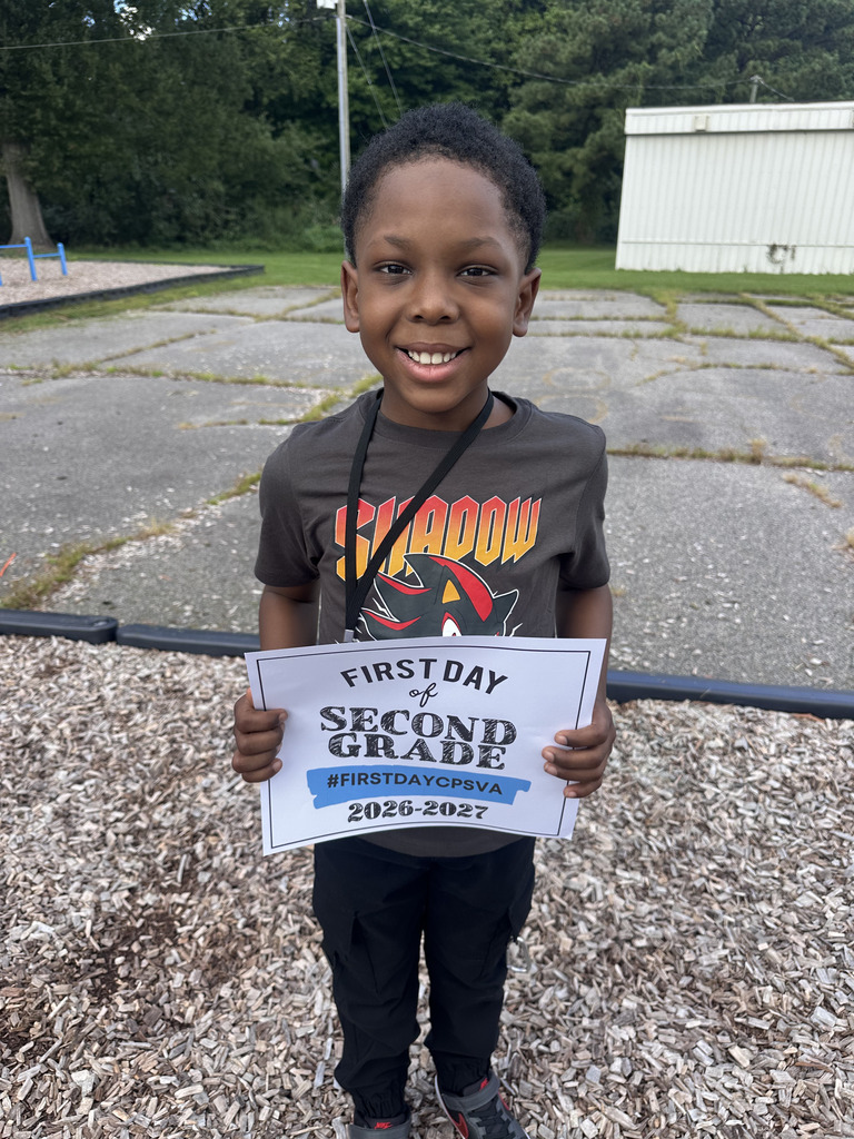 Second grade student poses with first day of school sign