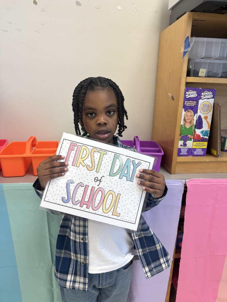 student poses with first day of school sign