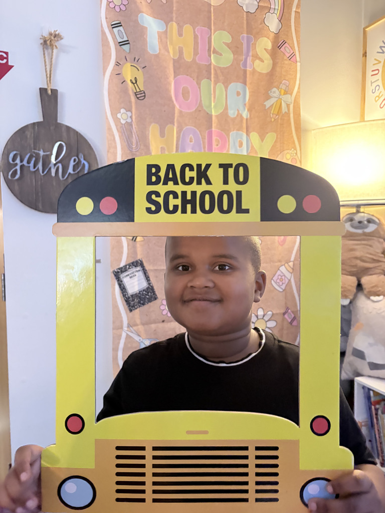 student poses with school bus photo prop