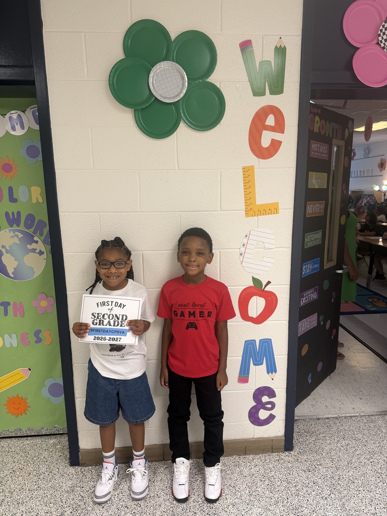 students pose with first day of second grade sign