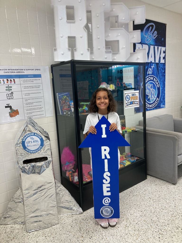 Student excited to be holding the I RISE at SRI arrow.