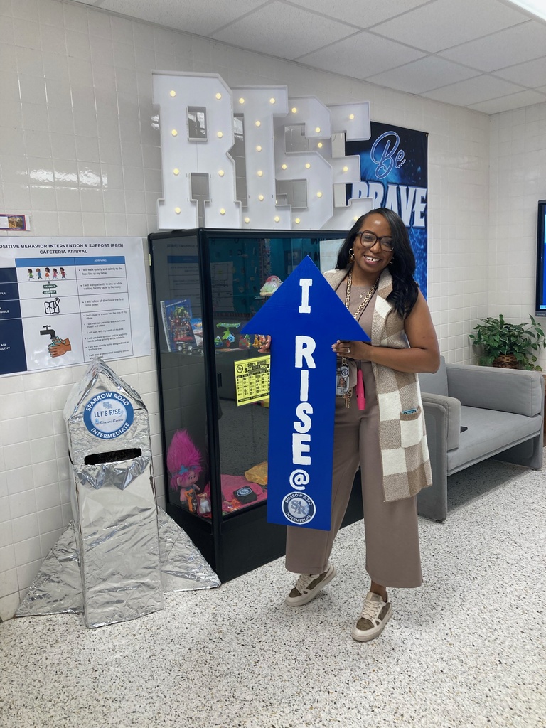 Mrs. Butler excited to be holding the I RISE at SRI arrow.