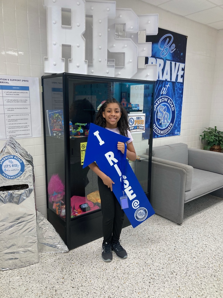 Student excited to be holding the I RISE at SRI arrow.