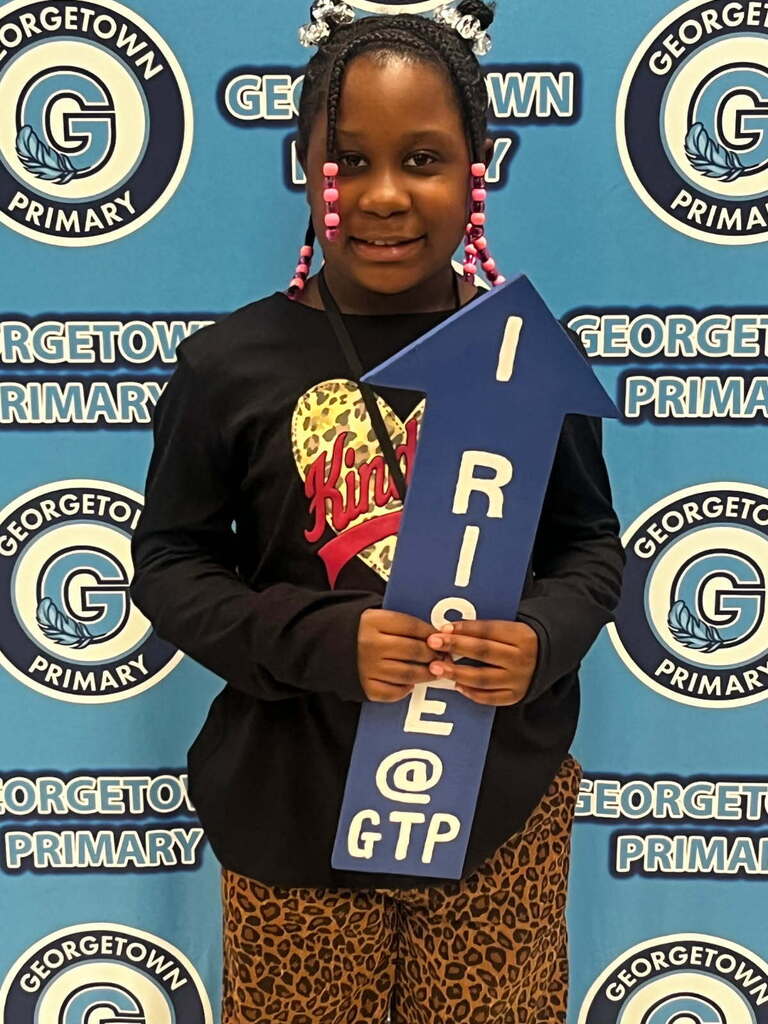 student poses with I RISE arrow for postiive office referral