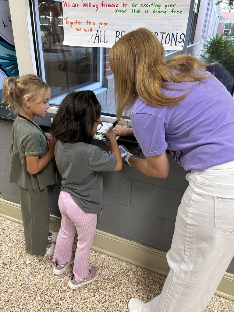 Students writing their name on their book from the book vending machine