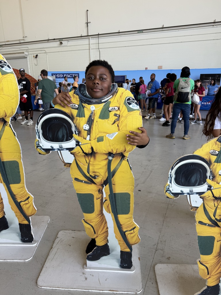 Student standing behind  a astronaut yellow suit.