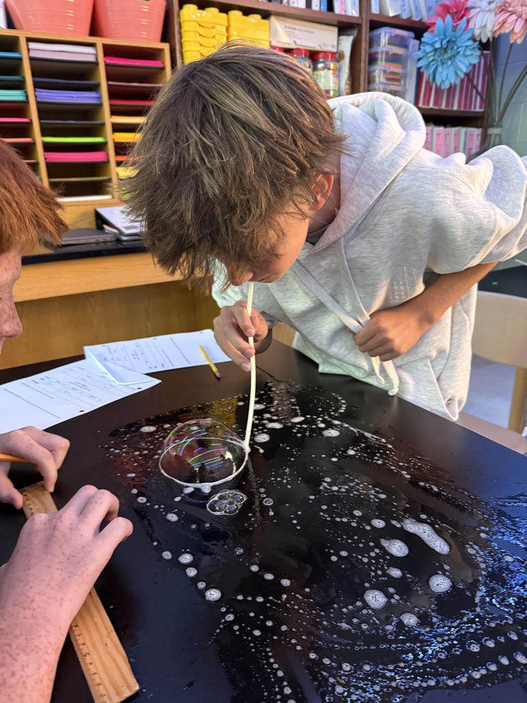 student blowing a bubble on the desk