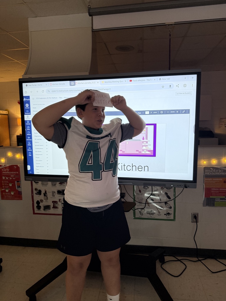 student holding the kitchen item he has to guess on his forehead as he listens to clues from his team