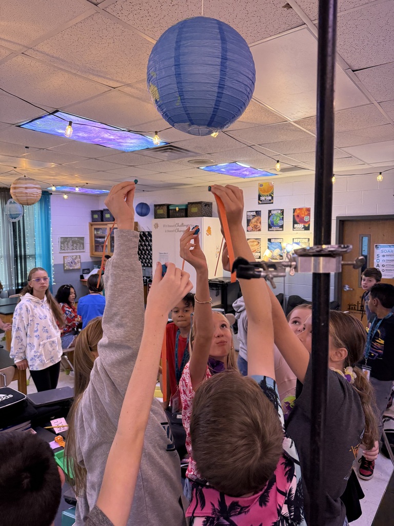 students holding up their creations for review