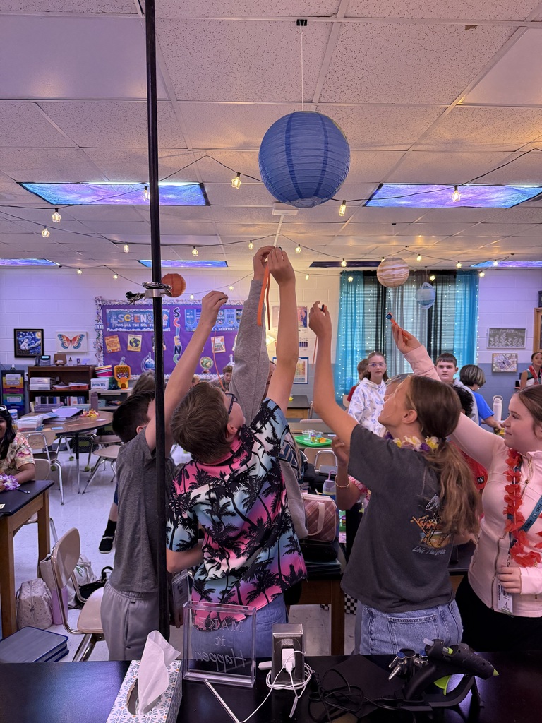 students holding up their creations for review