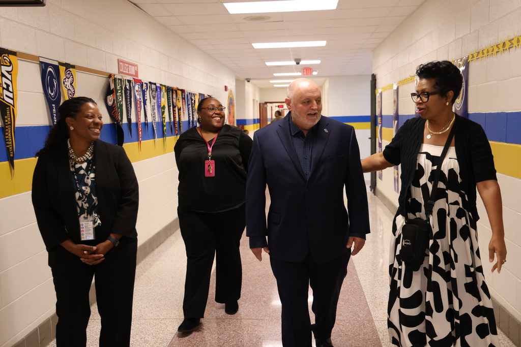 School administrators chatting while walking together down a school hallway.