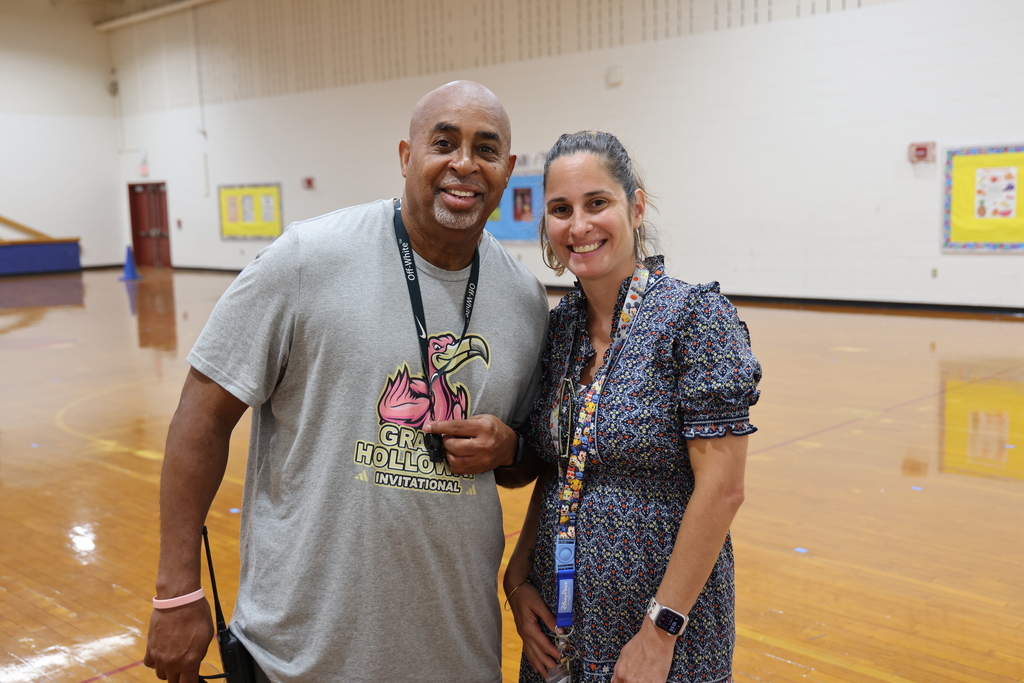 Two school staff members posing for a photo in the gymnasium.