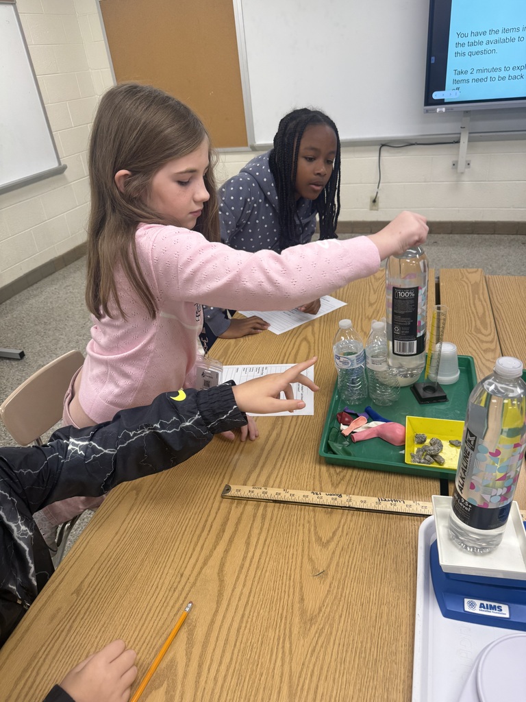 Student holding a bottle filled with some water above other science Lab materials.
