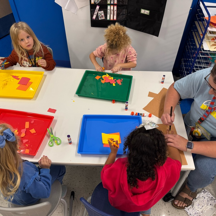 Preschool students doing art projects with the help of a teacher