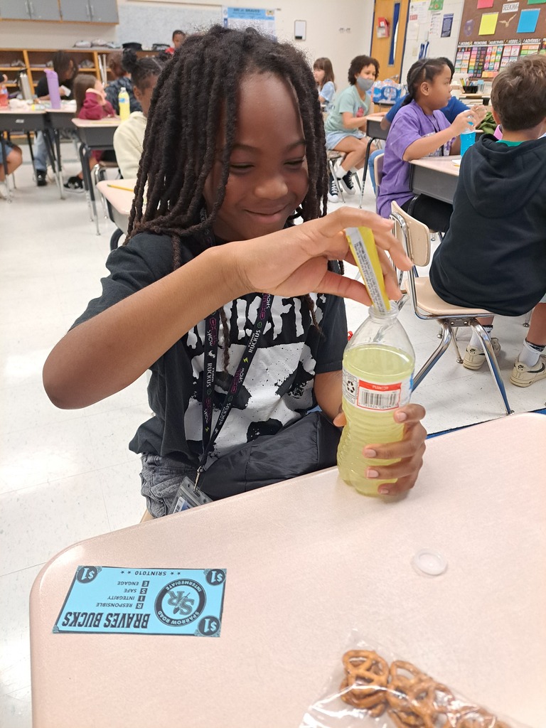 Student pouring lemonade powder into a water bottle.