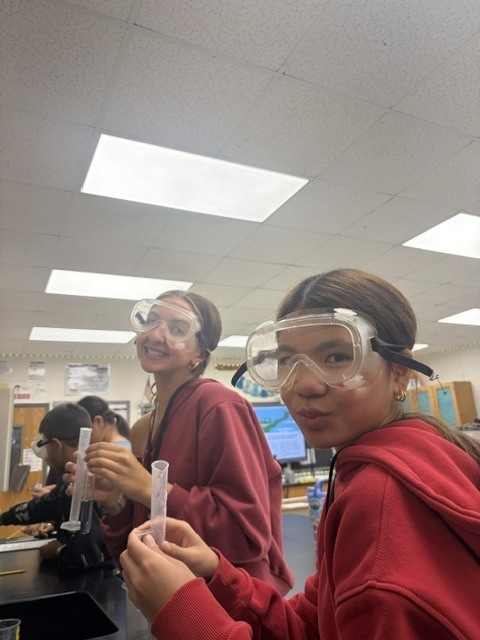 students smiling in their goggles as they prep for their lab
