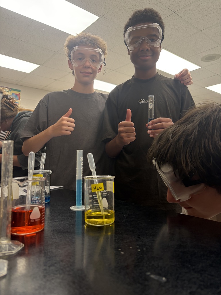 Students smiling with their goggles working in a lab
