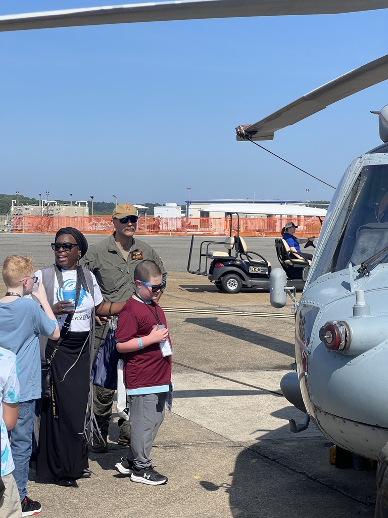 students and teachers with Navy pilot in front of airplane 