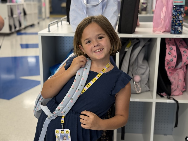 a student packed up, smiling, waiting for the end of the day