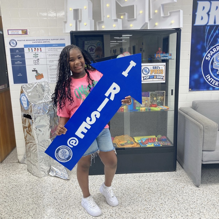 A student holding the I RISE arrow in the main lobby. 