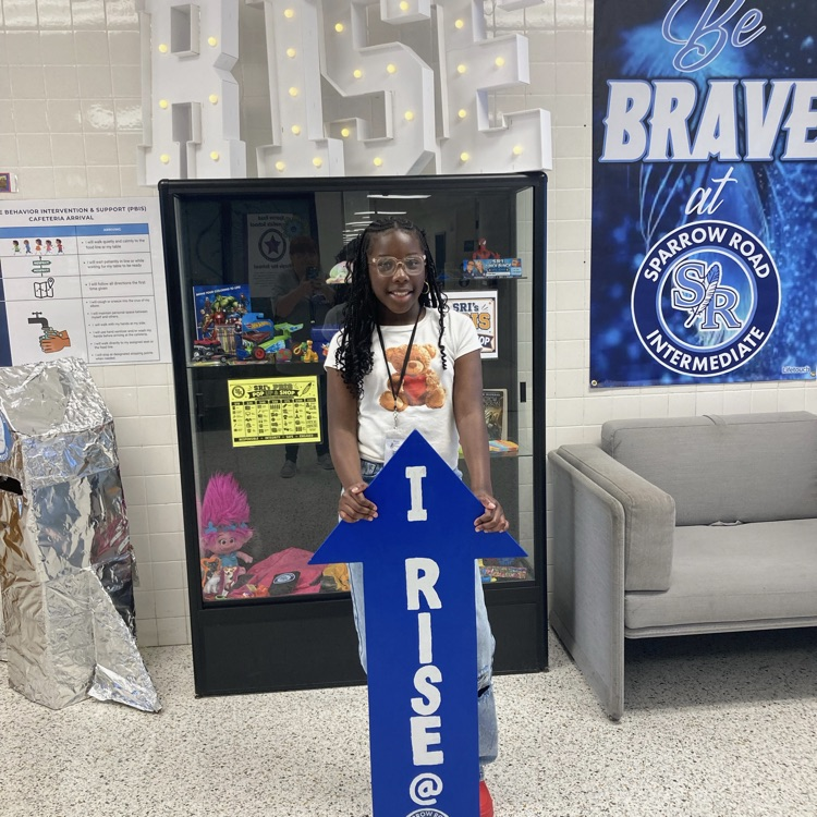 A student holding the I RISE arrow in the main lobby.
